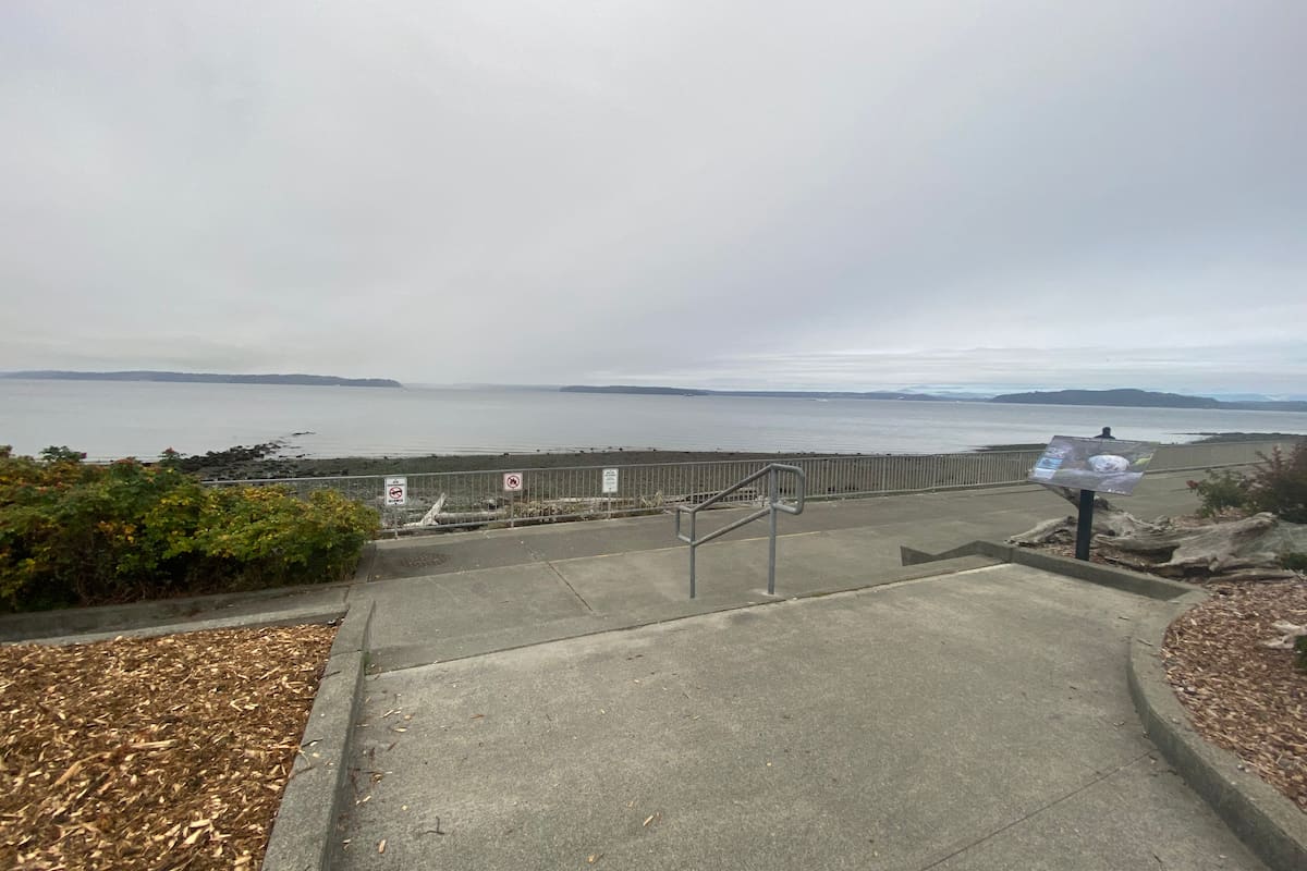 The entrance to the beach is marked by a set of stairs leading to a ramp on the left side.
