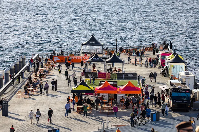 Large crowds gathered on Pier 62 for different activities. The waters of Elliot Bay are seen directly off the pier.